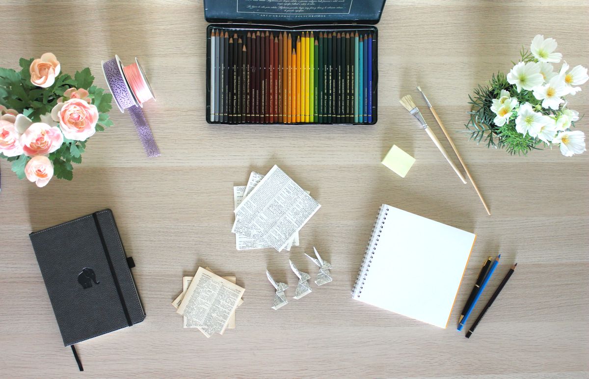 Papel, lápices de colores y materiales creativos sobre una mesa de madera